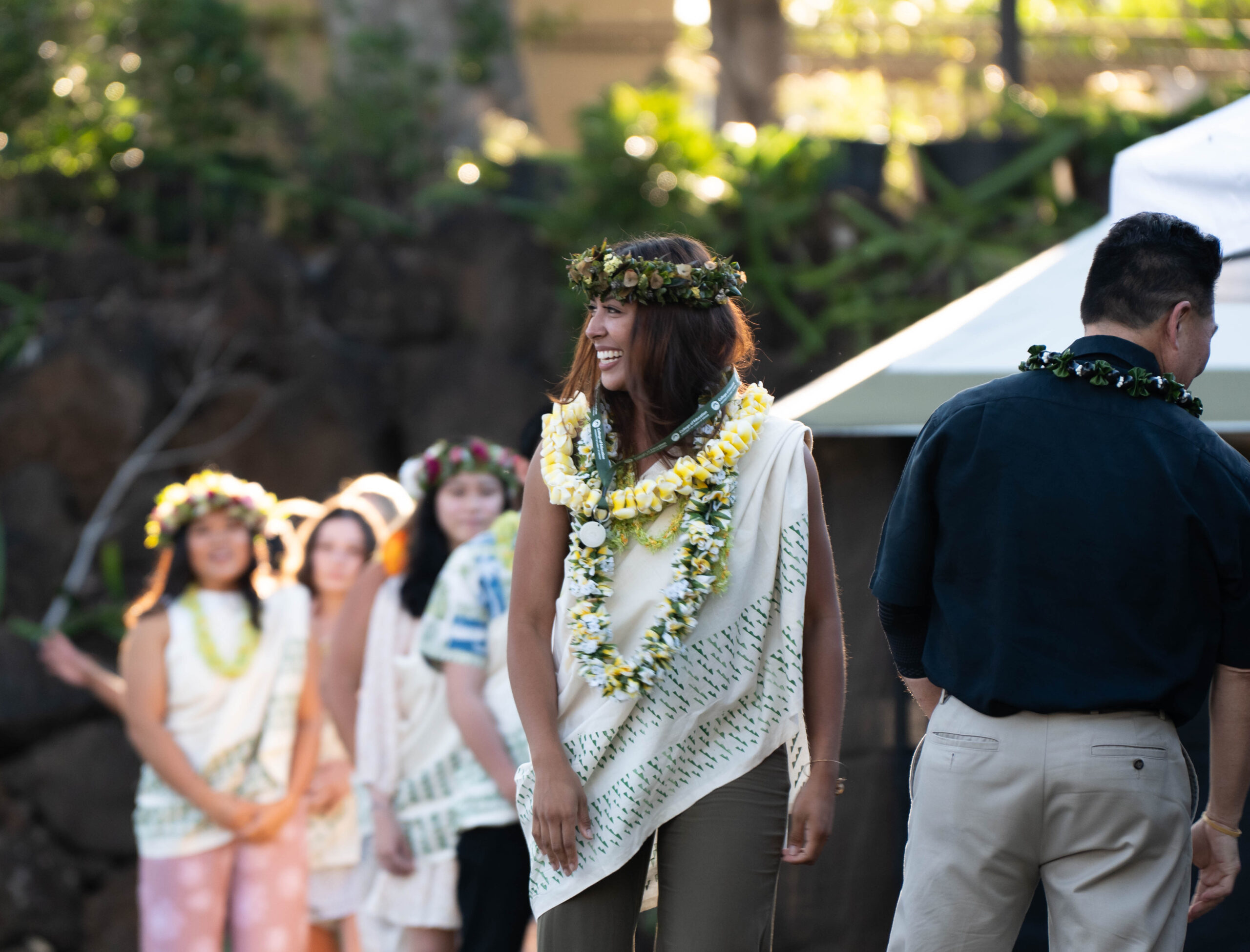 graduate walking across the stage wearing lei, kihei, and haku