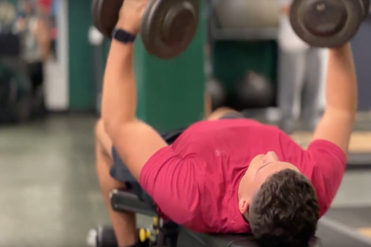 man lifting dumbbells in each hand while lying down on bench