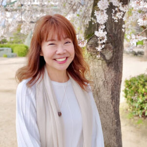 Linda smiling in front of a Japanese cherry blossom tree