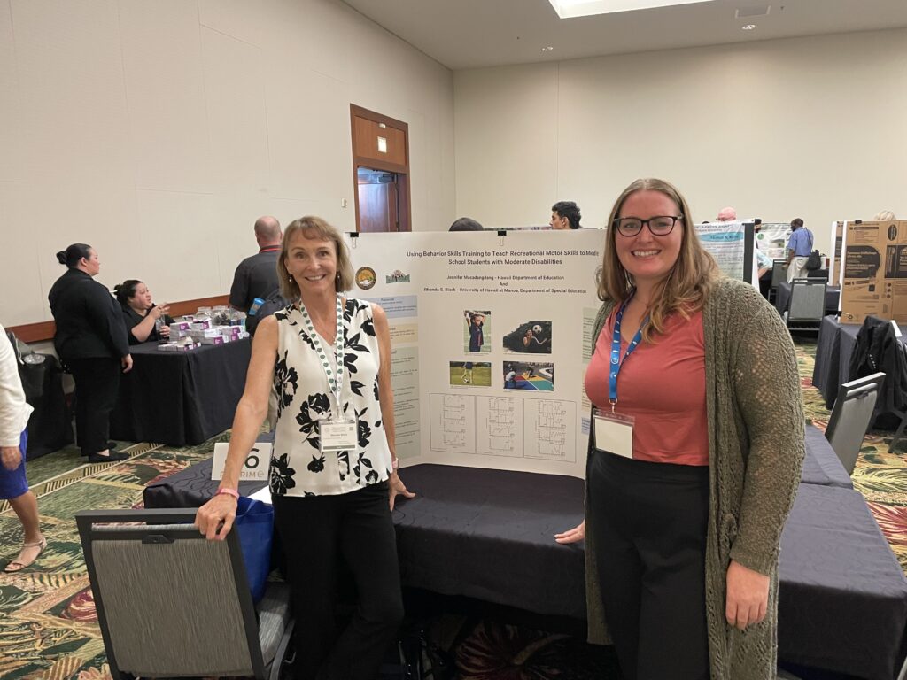 Jennifer and Dr. Black standing in front of a table displaying their research poster.