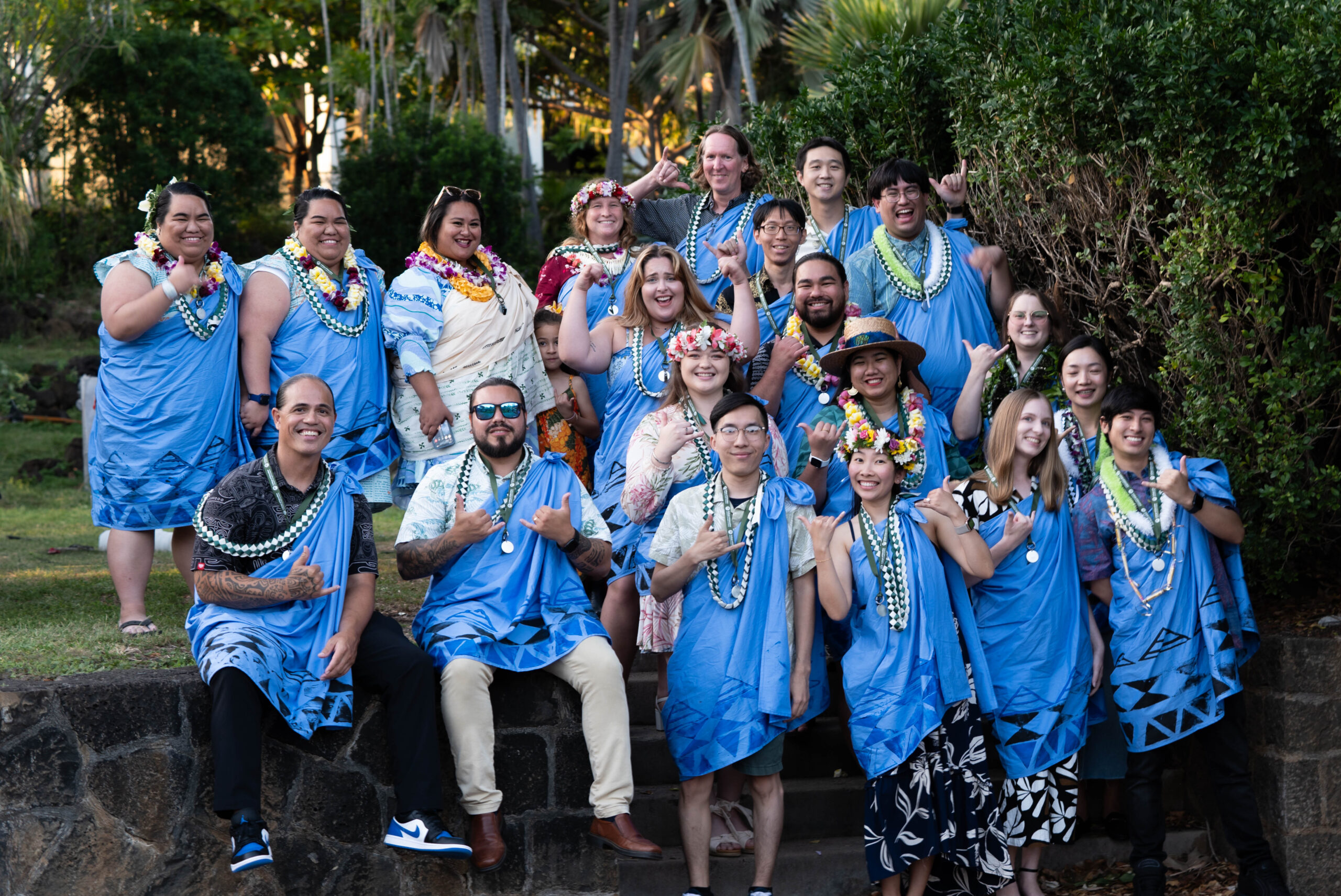 cohort grouped together at their graduation wearing blue kīhei